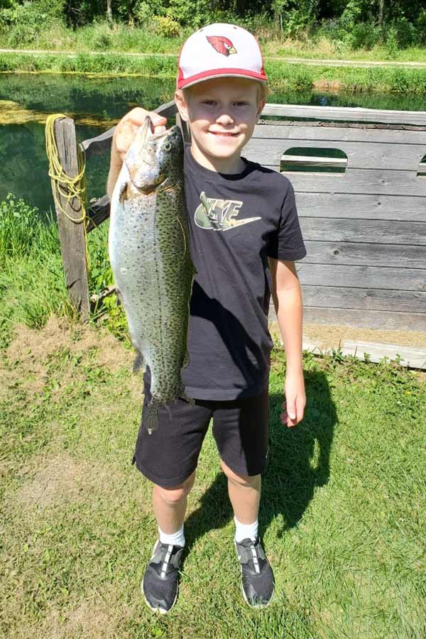 Boy in black shirt holds a trout