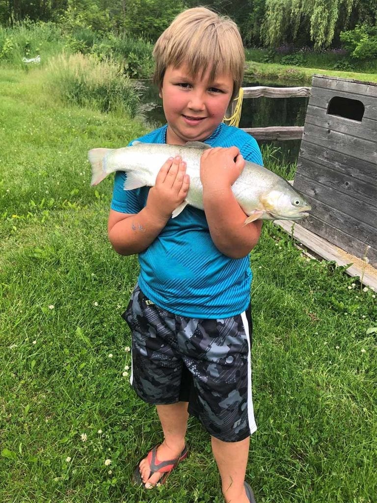 Boy in blue shirt hugs a trout